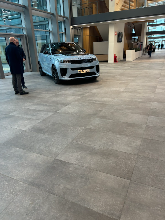 A new light blue Range Rover on display in a modern JLR building lobby.