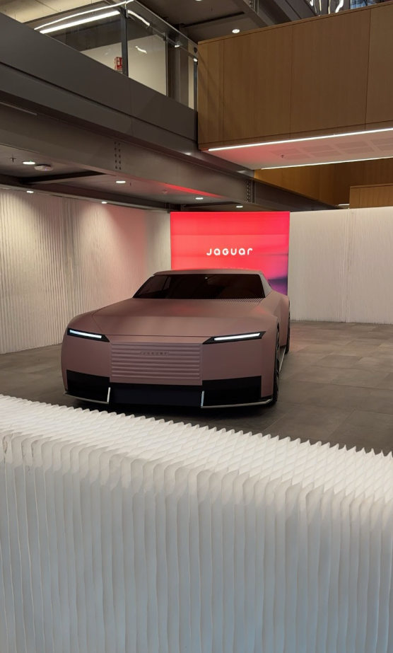 A new Jaguar car on display against a red backdrop.